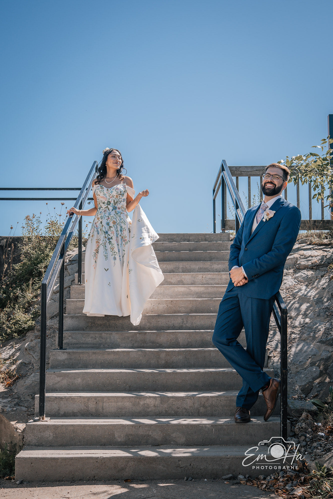 Mariés dans un escalier sous un ciel bleu