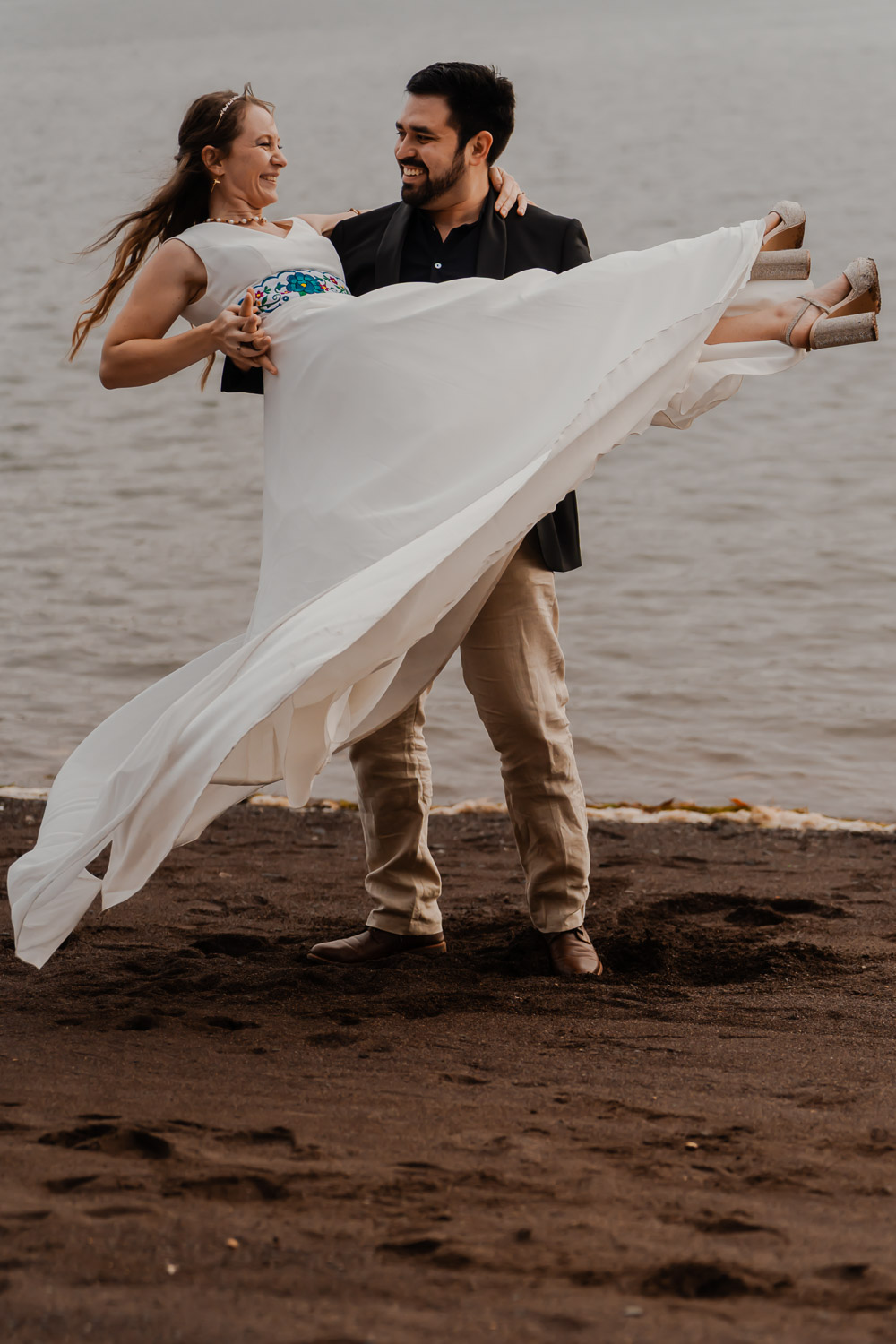 Marié portant sa mariée sur la plage